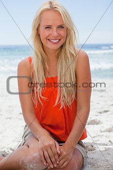 Young smiling blonde woman sitting on the beach