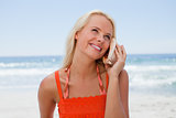 Young blonde woman listening to the sound of the sea through a s