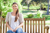Smiling woman relaxing in the park on a bench