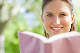 Smiling woman reading a book in the park
