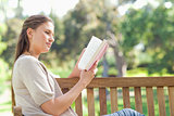 Side view of woman reading while sitting on a park bench