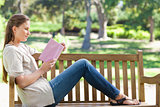 Side view of a woman reading a novel on a park bench