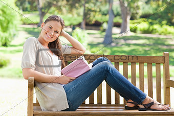 Side view of a smiling woman sitting on a park bench with her bo