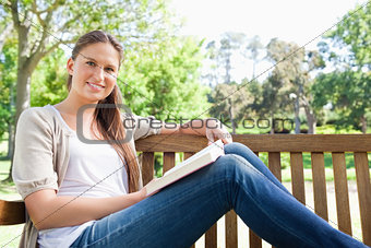 Smiling woman sitting on a bench with a book