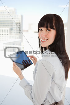 Woman looking into the camera as she holds a tablet pc in her ha