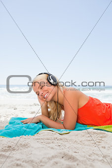 Young blonde woman lying down while listening to music