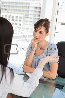 Brunette and black haired co workers chat to one another 