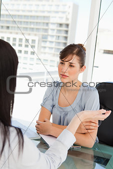 A brunette worker listens to her co-worker 