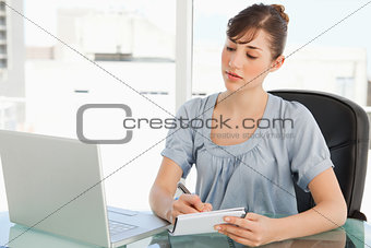A woman takes notes off of her laptop