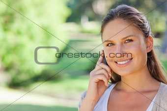 Smiling woman on her phone in the park