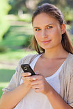 Close up of woman holding her cellphone in the park