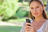 Close up of woman holding her mobile phone in the park