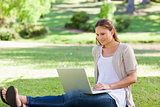 Woman sitting on the lawn with her laptop