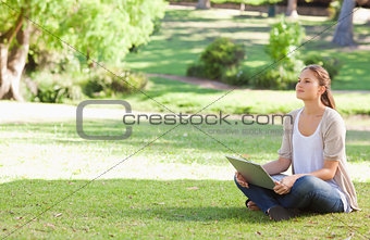 Woman sitting on the meadow with her notebook
