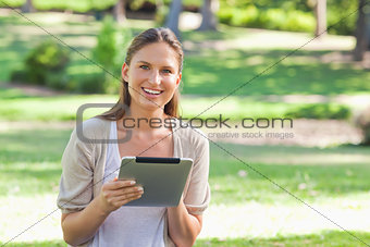 Smiling woman in the park with her tablet computer