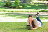 Woman laying on the lawn with a tablet computer