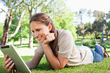 Smiling woman laying on the lawn with her tablet computer