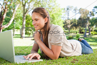 Smiling woman lying on the lawn with her notebook