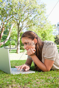 Woman lying on the lawn while using her laptop