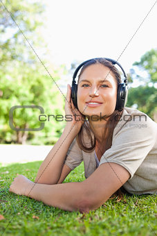 Woman with headphones lying on the grass