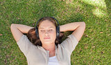Relaxed woman listening to music while lying on the lawn