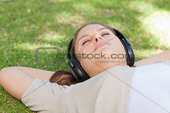 Relaxed woman lying on the lawn enjoying music
