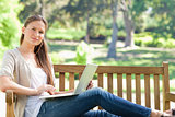Woman with her laptop on a park bench