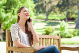 Laughing woman on her cellphone on a park bench