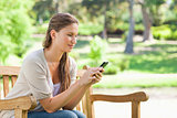 Woman reading a text message on a park bench