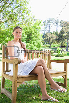 Woman with her legs crossed sitting on a park bench