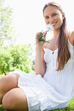 Smiling woman with a flower sitting on the lawn