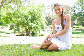 Smiling woman sitting on the lawn in the park