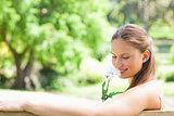 Side view of a woman smelling a flower