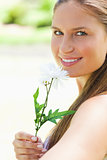 Close up of a smiling woman smelling a flower