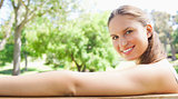 Side view of a smiling woman sitting on a park bench