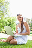 Smiling woman on the lawn with her laptop