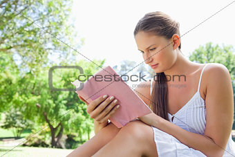 Side view of a woman reading a novel in the park