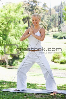 Smiling woman doing yoga exercises in the park