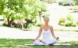 Woman sitting in a yoga position in the park
