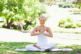 Smiling woman sitting in a yoga position on the lawn