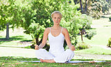 Woman sitting on the meadow doing yoga exercises