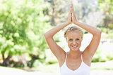 Relaxed smiling woman doing yoga in the park