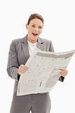 Surprised businesswoman standing reading the newspaper