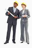 Businessman and woman with notes and hard hats
