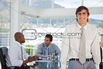 Smiling young businessman leans on table