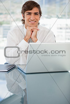 Smiling young businessman resting his head on his hands
