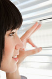 Close up of a woman looking out through blinds