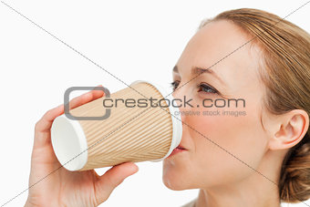 Close-up of a woman in a suit drinking a takeaway coffee