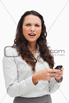 Portrait of a brunette grimacing while looking her text message