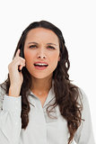 Portrait of a brunette grimacing while phoning 